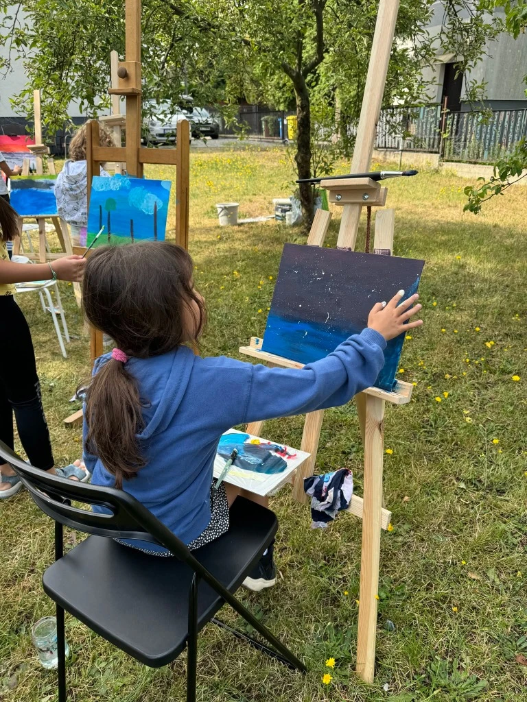 Dziewczynka malująca na sztaludze podczas warsztatów plenerowych Summer Camp w BeeReady